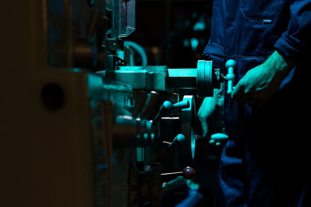 A technician working a machine by hand in low light