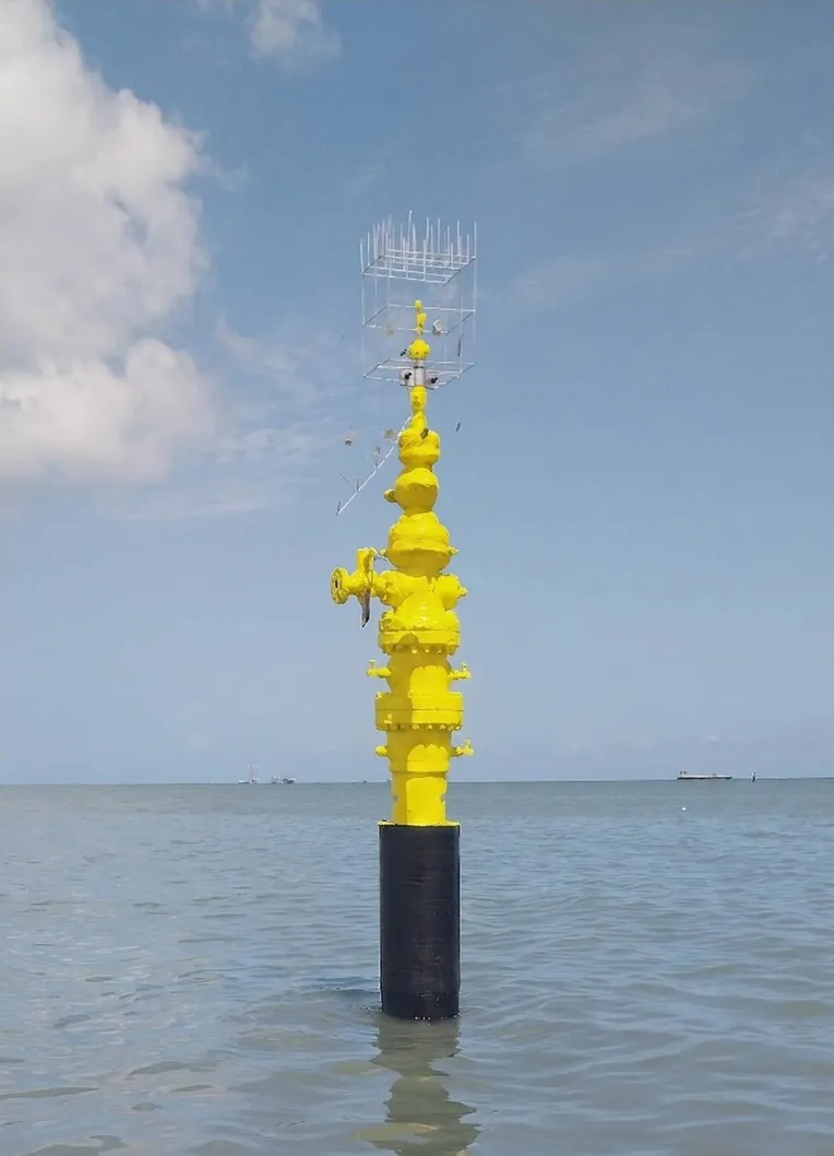 The repaired conductor standing in open water, its yellow wellhead above the composite-wrapped splash zone